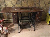 Full view of Singer sewing table base showing wooden top with compartments for sewing machine, cast iron base with pedal, and drawers on both sides.