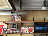 Shelves showing boxed power tools and a tool case including Black & Decker finishing sander, Skil Multi-Tasker, Jobmate Jigsaw, Shark Turbo Hand Vacuum, and Delta tool case