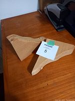 Pair of used wooden shelf braces with natural wood finish and one showing white paint residue.