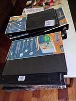 Multiple black binder folders stacked showing front and side views with QuickFit branding and labels.