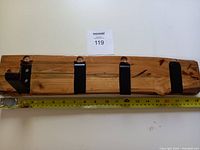 Full view of handcrafted folding wall hooks on a maple plank with measuring tape showing length approximately 19 inches and width about 4 inches.