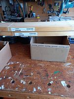 Photo of two boxed wooden bed slats labeled IKEA LURÖY placed on a workbench, capturing the packaging and item condition.