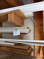 Photo showing stacked white baseboard mouldings mostly full-length of 8 or 10 feet, around 6 inches wide, with some cut ends visible.