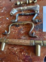 Photo of six vintage cabinet pulls of various sizes and styles arranged on a wood surface.
