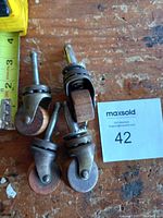 Photo showing all 4 vintage swivel casters with wooden wheels laid on a wooden surface next to a measuring tape for size reference.