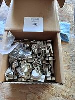 Box containing 23 pairs of soft close cabinet hinges and screws, showing hinges with metallic chrome finish inside a cardboard box.