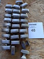 Set of 45 cabinet pulls organized in rows on a wooden surface showing their rectangular shape and metallic finish.