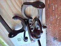 Four cast iron antique coat hooks on a wooden board with a label marked 68.