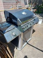 Overall left-front angle view of stainless steel and black Centrobbq 6800 gas BBQ grill showing front control panel with five knobs and side shelf with a handle.