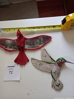 Full overview of both bird plaques side by side with a measurement tape showing size reference