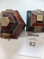 Two artisan wood jewelry cases, one hexagonal and one square, shown from top view, both with metal clasps and brass accents.