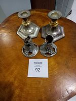 Four sterling silver candleholders on wooden table showing size and base shapes.