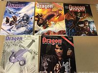 Photo of all five vintage TSR Dragon magazines showing various fantasy cover art and condition.