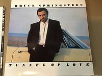 Photo of the Bruce Springsteen Tunnel of Love album cover showing the artist leaning on a car, clear and clean cover artwork.