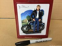 Photo of the James Dean heirloom ornament box showing the packaged figurine with a Sharpie pen as size reference.