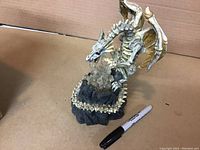 Full view of the dragon statue showing skeletal bone structure, detailed wings, and rocky base with crystals.