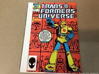Front cover of Transformers Universe #1 comic book showing Bumblebee on a red background with robot faces.