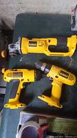 Photo showing all three DeWalt cordless tools laid out on a table: the drill/driver, clutch driver, and cutoff tool in yellow and black.