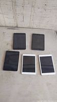 Five iPad mini devices arranged in two rows on a flat surface