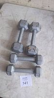 Four hex dumbbells placed on the floor, two labeled 5 lb and two labeled 10 lb, showing wear and rust.