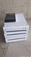 Three stacked white Nintendo Wii consoles with one black external hard drive on top