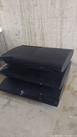 Three black PlayStation 3 consoles stacked, showing cosmetic wear and untested condition.