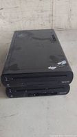 Photo shows two black Nintendo Wii U consoles stacked on a flat surface, visible wear and scratch marks on top console.