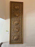 Front view of tall narrow framed fabric art with five circular elephant designs in gold.