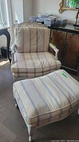 Chair and matching ottoman showing upholstery fabric and wooden frame with carved detail