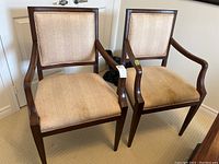 Pair of wood-framed chairs with beige fabric cushions on seat and backrest, showing from front angle.