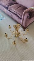 Photo of the gold tone chandelier on the floor showing the six arms and central hanging loop.