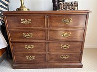 Front view of Sligh wood dresser showing eight drawers with brass pulls and surface wear.