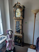 Full view of the grandfather clock showing its height, decorative case, and surroundings for scale.