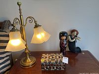 Full lot view showing the metal lamp, hinged mosaic box, wooden figure, and plush figure on a wooden surface against a wall.