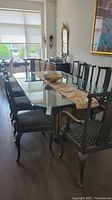 Glass top dining table with two black pedestal bases and eight chairs around it in dining room