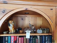 Wide view of the shelf showing a ceramic lion figurine, black animal figurine, clear glass elephant, brass trinket box, and zebra patterned box.