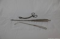 Top view of three antique metal dental tools laid on white cloth