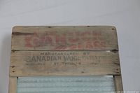 Close-up of top wooden panel with red and black stamped text showing maker and brand information.