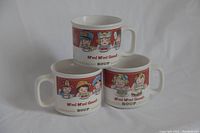 Three white ceramic Campbell Soup mugs with colorful vintage cartoon characters and Campbell Soup branding, set on a white backdrop to show full lot.