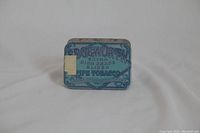 Front view of the rectangular metal tin with blue vintage lithograph advertising on the lid reading 'Edgeworth Extra High Grade Sliced Pipe Tobacco'.