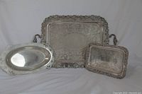 Three silver trays grouped with one large rectangular tray in back and two smaller trays in front.
