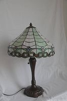 Full view of the Tiffany style table lamp showing the bronze base and multi-colored stained glass shade