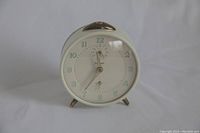 Front view of clock showing white dial, glow-in-the-dark numerals and metal case