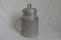 Photo showing the vintage metal milkcan with lid on, displaying its cylindrical shape and side handle.
