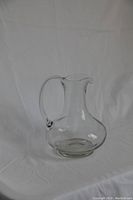 Clear glass wine carafe with handle shown from front angle on white background