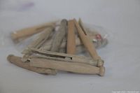 Two sets of 12 wooden clothes pins, total 24 pins, displayed on a white surface, some resting inside a plastic bag.