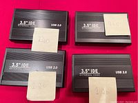 Four black 3.5 inch IDE external hard drive enclosures showing USB 2.0 label. Each has a sticky note with hard drive capacity (three 120 GB and one 160 GB).