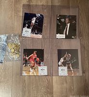 Four signed 8x10 basketball photos with authentication certificates and a bag of gold-toned hockey coins on wood floor