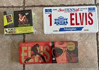 Photo showing Elvis Presley trading cards pack, official Elvis license plate, and Russell Stover Elvis-themed chocolate tin