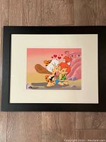Framed serigraph showing Pebbles and Bam Bam in a prehistoric setting with hearts above their heads.